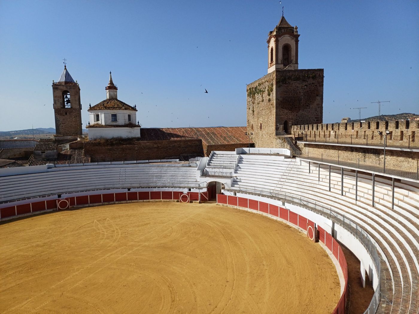 Plaza de toros con la torre del homenaje a la derecha. En la otra parte, el campanario y en en el centro la cúpula